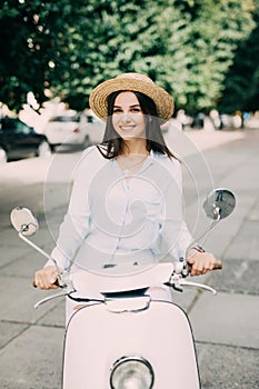 Beautiful girl in a hat in a white t-shirt and hat posing on a scooter
