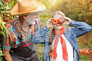 Beautiful girl having fun in organic apple orchard her grandfather