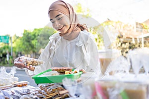 A beautiful girl in a headscarf holding a snack wrapped in plastic will be bought