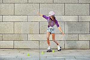Beautiful girl in a helmet learns to ride on roller skates holding balance