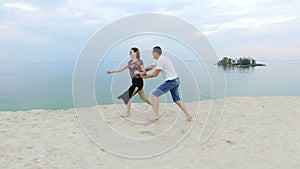 Beautiful girl and her boyfriend playing on the seashore - the guy doganyaet girl and kisses her