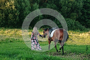 Beautiful girl with her horse on a lovely meadow lit by warm light