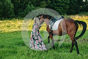 Beautiful girl with her horse on a lovely meadow lit by warm light