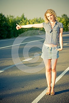 Beautiful girl hitchhiking on the road