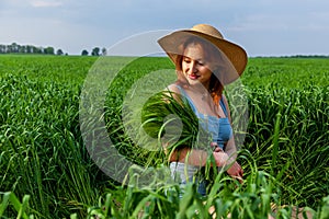 beautiful girl holding a bouquet of ears of green wheat