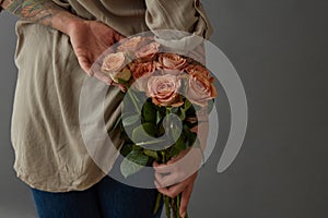 Beautiful girl holding a cappuccino rose behind her back.