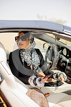 A beautiful girl holding her smartphone in her hands is sitting in the car. A female driver reads a message and chats on