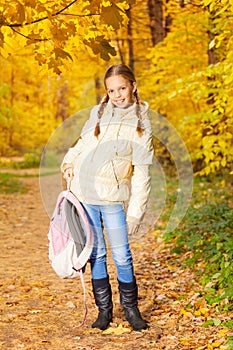 Beautiful girl holding rucksack standing in forest