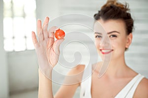 Beautiful girl holding up cherry tomato