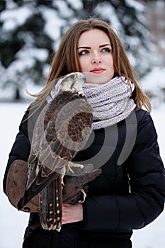 A beautiful girl holds a falcon