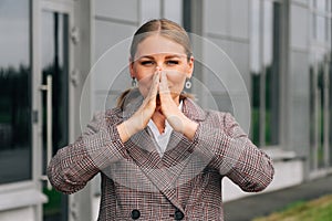 A beautiful girl holds her hands on her nose because of a disease during the flu runny nose