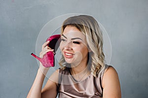 Beautiful girl holds a pink shoe in her hand