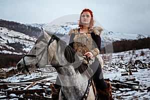 Beautiful girl on horse and with red hair in armor. Woman is a Viking. Fantasy