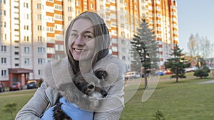 Beautiful girl hugs cute little dog after visits vet. A girl walks on the street with a small dog after surgery