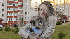 Beautiful girl hugs cute little dog after visits vet. A girl walks on the street with a small dog after surgery