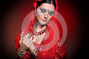 Beautiful girl in the image of Indian woman in a red sari with beautiful patch acrylic nails in oriental style in the studio