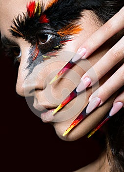 Beautiful girl in image of Phoenix bird with creative makeup and long nails. Manicure design. beauty face.