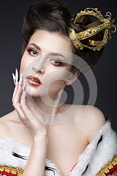 Beautiful girl in the image of the Queen in the mantle with a crown on the head and long nails. Beauty face.