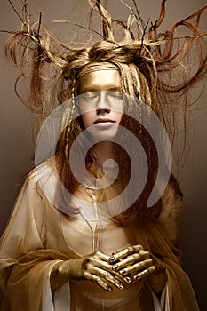 Beautiful girl in the image of a tree with branches in her hair. The model with creative make-up.