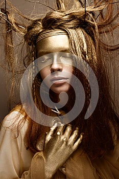 Beautiful girl in the image of a tree with branches in her hair. The model with creative make-up.