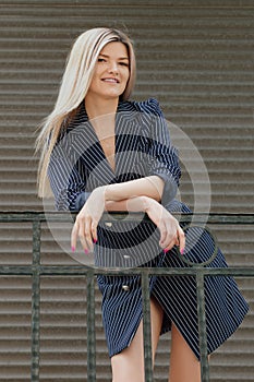 Beautiful girl in jacket-dress standing on balcony