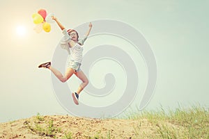 Beautiful Girl jumping with balloons on the beach