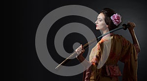 Beautiful girl in kimono with japanese sword katana on a black