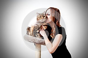 Beautiful girl kissing her cat on neutral background.