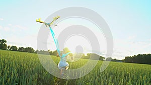 Beautiful girl with kite flying in wind running on wheat field in sunset. Freedom beayty health happiness concept. Happy