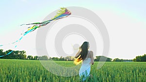 Beautiful girl with kite flying in wind running on wheat field in sunset. Freedom beayty health happiness concept. Happy