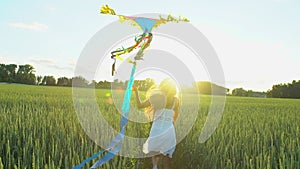 Beautiful girl with kite flying in wind running on wheat field in sunset. Freedom beayty health happiness concept. Happy