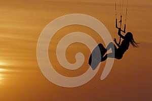 Beautiful girl kitesurfing jump at golden hour womanl jumping kiteboarding silhouette at sunset