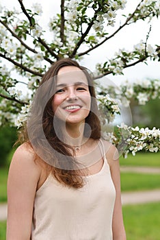 Beautiful girl laughing against the background of a young flowering Apple tree