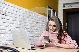 Beautiful girl smile using multiple devices phone and laptop on a table at home photo