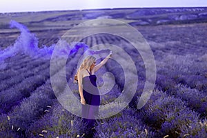 Beautiful girl on the lavender field with colored smoke Beautiful woman in the lavender field on sunsete