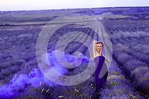 Beautiful girl on the lavender field with colored smoke Beautiful woman in the lavender field on sunsete