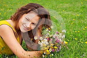 Beautiful girl laying on grass with bouquet