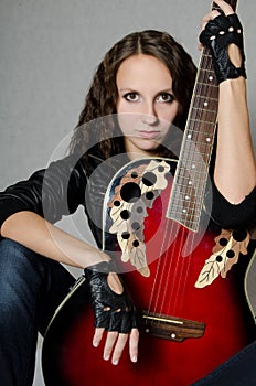 Beautiful girl in a leather jacket with a guitar