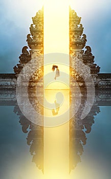 Beautiful Girl Levitating Near Gates Of Heaven In Pura Lempuyang Temple In Bali, Indonesia.