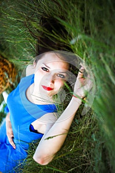 Beautiful girl lies on the grass with a basket and bread