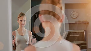 Beautiful girl lifts dumbbells up and looks at herself in the mirror on workout