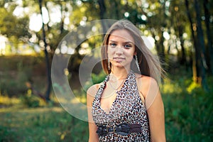 Beautiful girl in a light sarafan with developing hair on forest background. Girl is smiling standing.