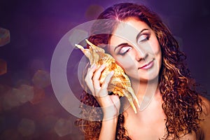 Beautiful girl listening to sea music in sea cockleshell