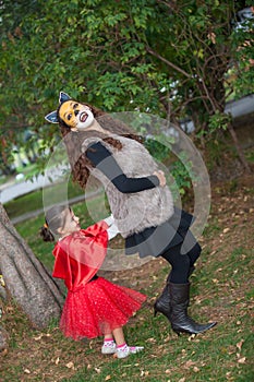 Beautiful girl on little red riding hood costume playing with her mom. Real family having fun while using costumes of the Little