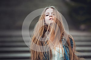 Beautiful girl with long blond hair blowing by wind. Toned image