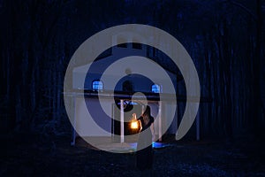 Beautiful girl in long dress with lantern alone in the dark forest