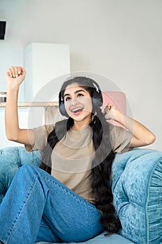 Beautiful girl with long hair and in headphones chills on couch