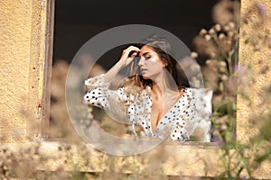 The beautiful and girl with long hair stands by the window.Portrait of a pensive woman looking away through a window.