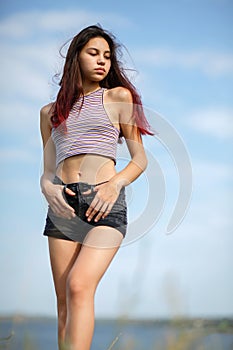 Beautiful girl with long hair strolling on a bank of a river, rest at weekends on a blurred natural background.