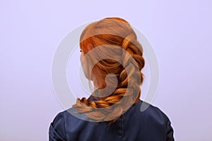 Beautiful girl with long red hair, braided with a French braid, in a beauty salon.